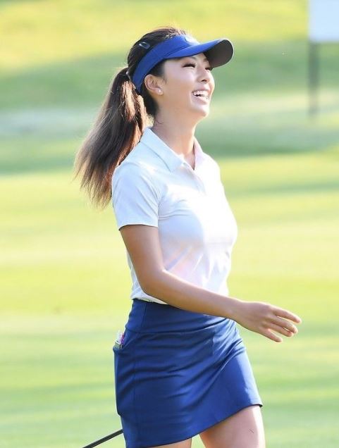 cute golf outfit for women with a blue skirt, a white shirt, and a blue visor